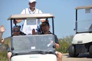 Picture of men waving to the camera on a golf cart at the golf tournament 