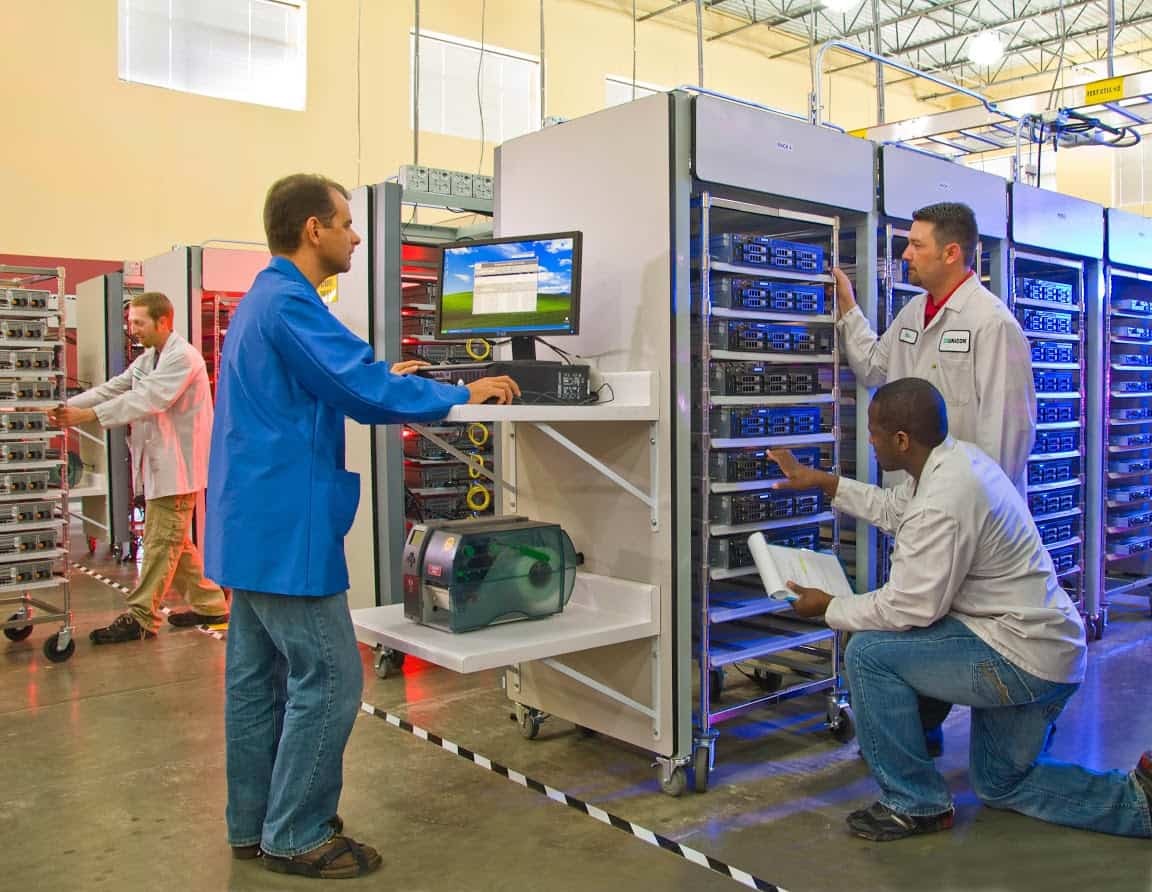 Picture of people working in a warehouse with computers, servers, etc. 