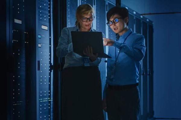 employees on a laptop next to a wall of servers